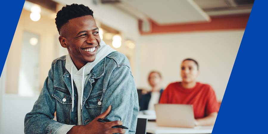 A college student smiling at a desk