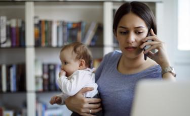 Mother holds her baby while on the phone