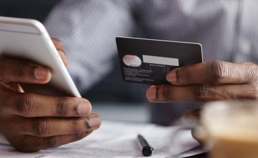 Person holding a phone and checking credit card.