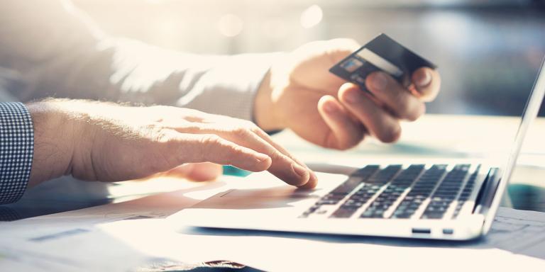 Person holding a credit card while using a laptop