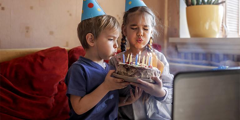 A brother and sister blow out candles while on a video call
