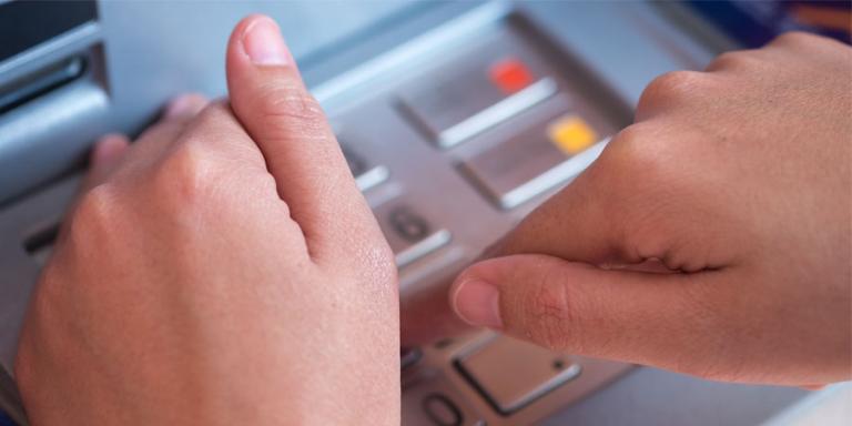 woman hiding her PIN on an ATM