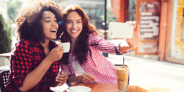 Two friends taking a selfie over coffee.