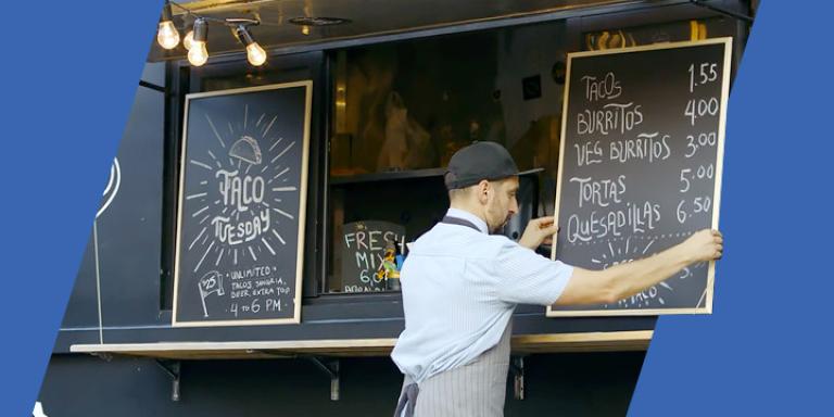 Man putting up sign at taco truck