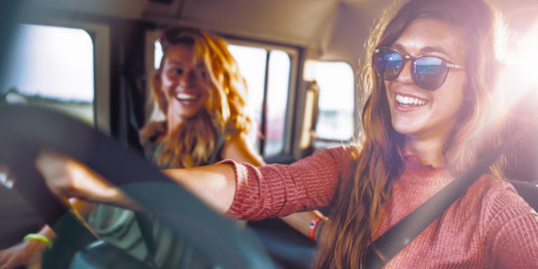 Woman driving a car with sunlight shining behind her.