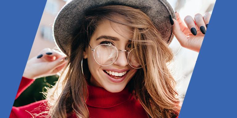 Woman with red sweater, round glasses, and hat