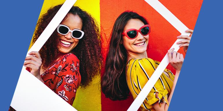 Two woman wearing sunglasses standing back-to-back