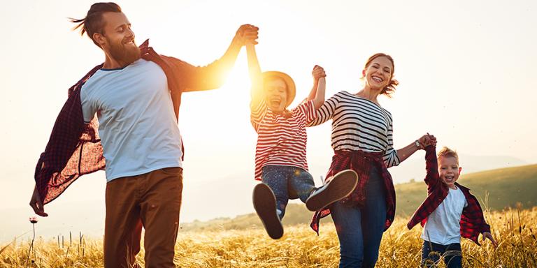 Family cavorting in a field with a sunset in the background.