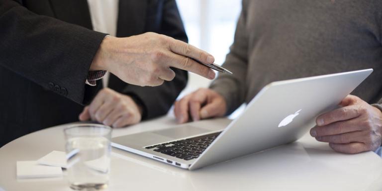 Financial advisor helping a client on his laptop.