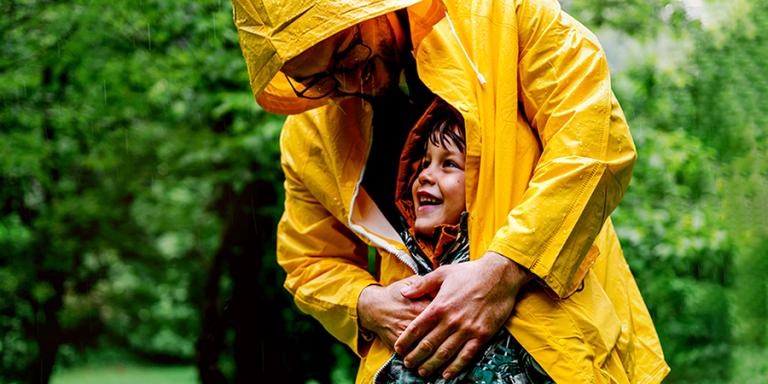 Father and son in yellow raincoats in the rain