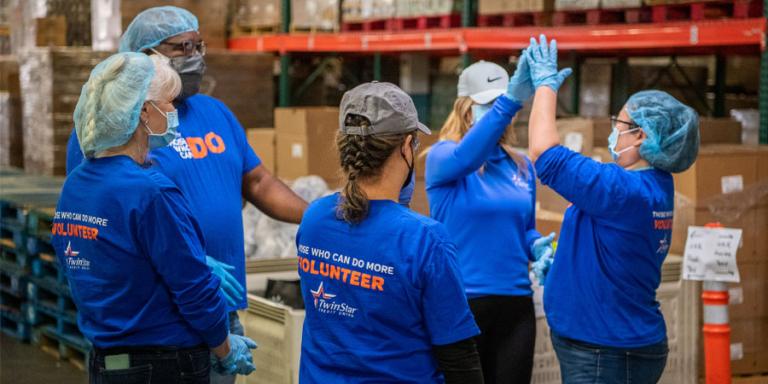 TwinStar employees high fiving each other at a volunteer event.