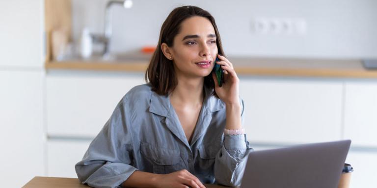 Concerned woman talking on the phone while on a laptop.