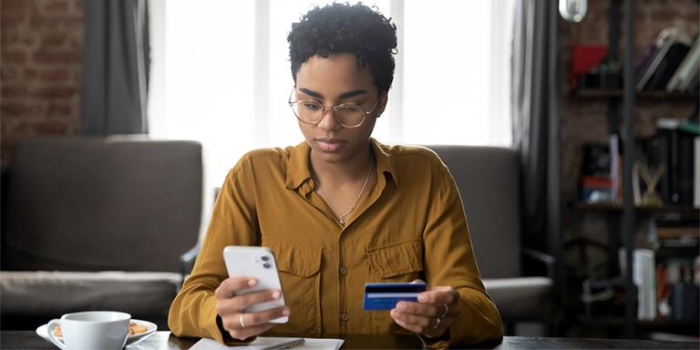 Woman holding gift card and smart phone