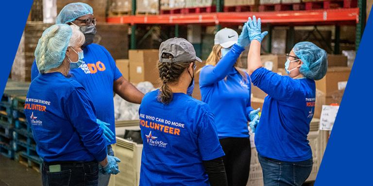 TwinStar team high-fiving at a food packing event.