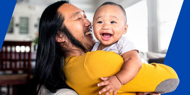 Father holding baby in their home