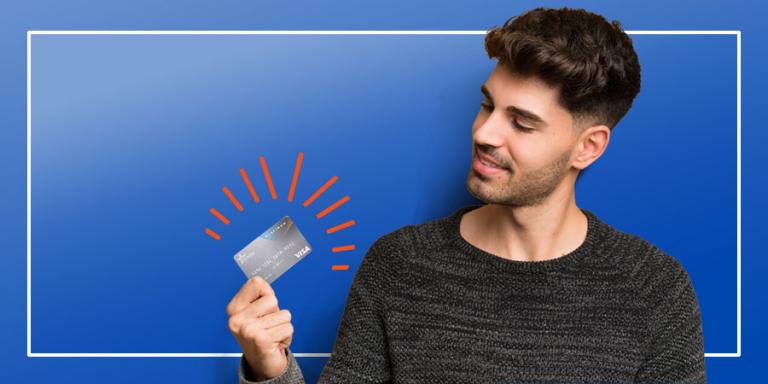 Man on a blue backgroun looking at his credit card.