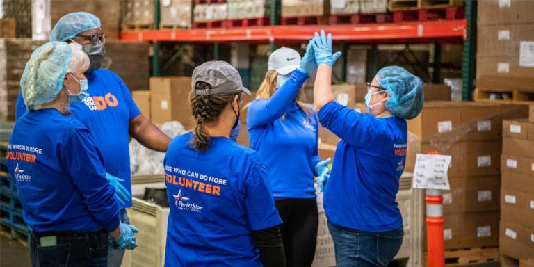 TwinStar team high-fiving at a food packing event.