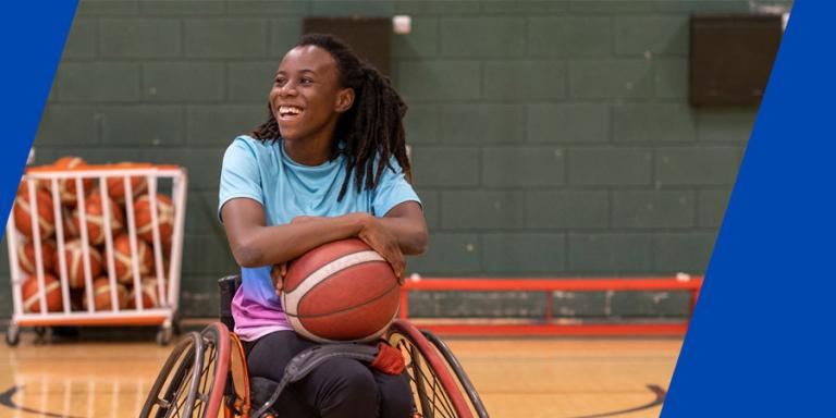 Black basketball athlete in her wheelchair smiling and ready for a game of hoops.