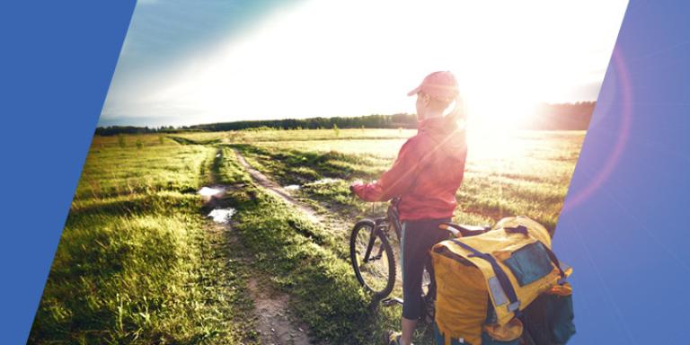 Avid cyclist with a mountain bike enjoying the sunrise over a meadow.