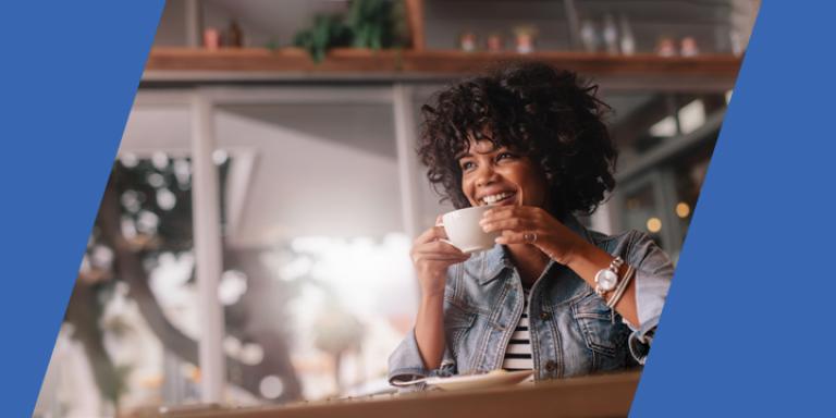 A laughing woman drinking a small coffee