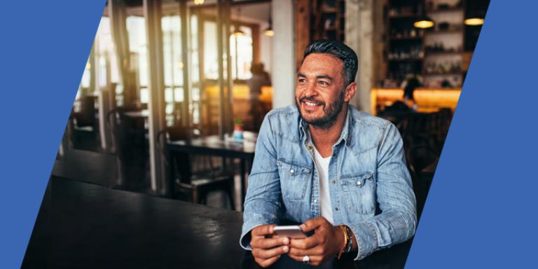 Smiling man in cafe holding a smartphone