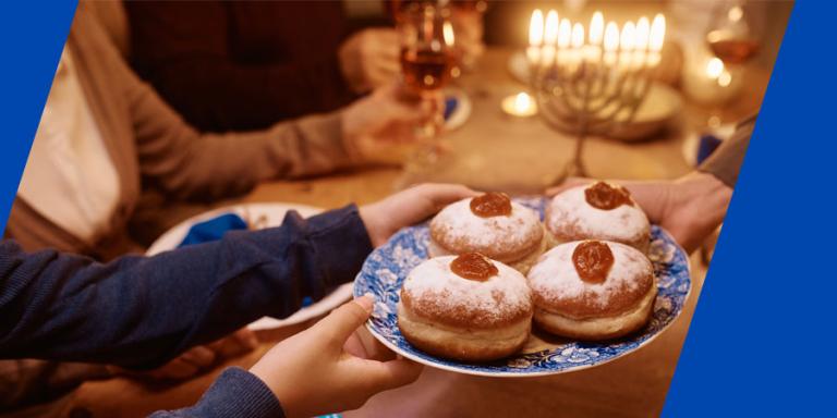 Close up of Jewish family having Hanukkah jam filled donuts for dessert at dining table.