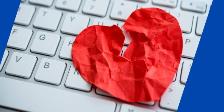 Crumpled and torn paper heart on a white keyboard.