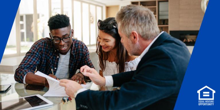 First time home buyers signing paperwork with a real estate agent.