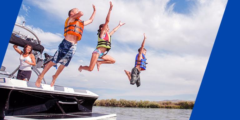 A group of children jumping into a lake from a boat.