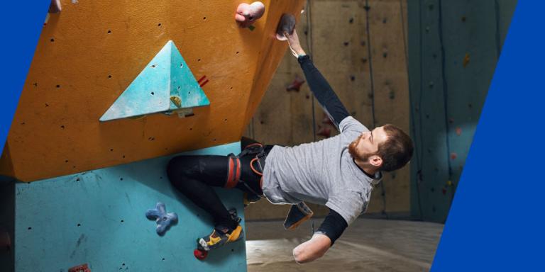 One armed athelete climbing a rock wall.