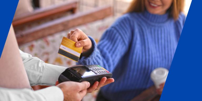 Woman with credit card using payment terminal at a cafe.