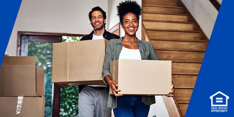 Man and woman carrying boxes into their new home