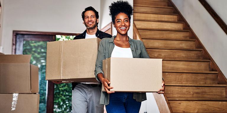 Man and woman carrying boxes into their new home