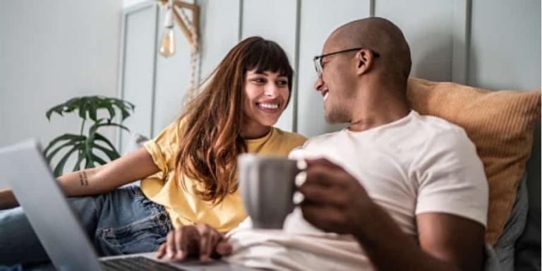 a couple reclining while using a laptop.