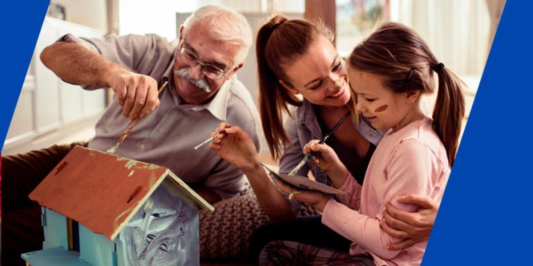 Grandfather, mother and daughter are painting a birdhouse together.