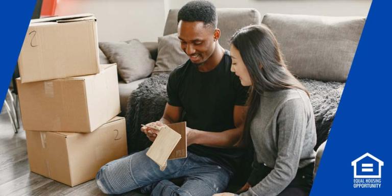 a couple on the floor of a house unpacking boxes