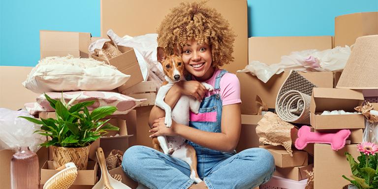 A women holding a dog in front of a lot of moving boxes