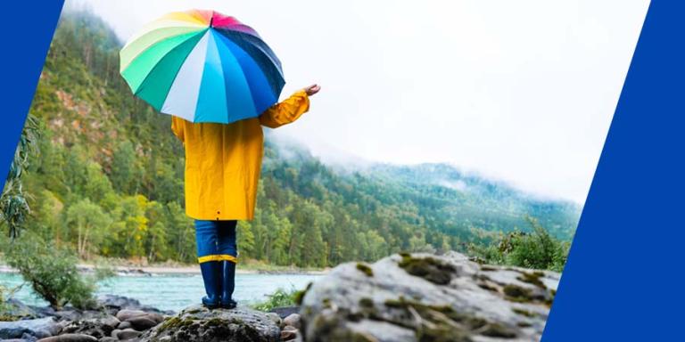 a person in the rain holding a rainbow umbrella
